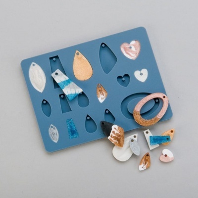 Moldes de silicone azul para joias com peças coloridas e texturizadas em branco, azul, castanho e rosa