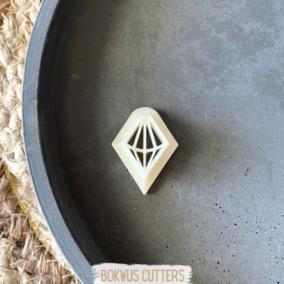 Cortador de massa geométrico branco numa bandeja cinzenta com textura e borda preta