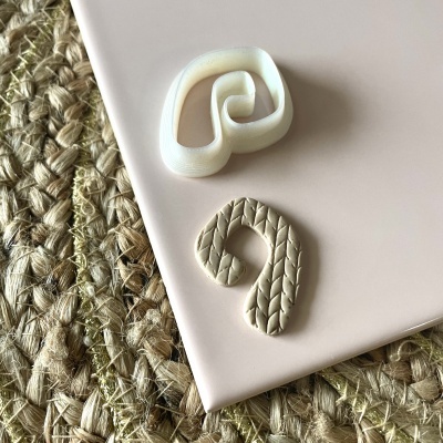 Dois moldes de cortador em forma de folha sobre superfície rosa e tapete de fibras naturais