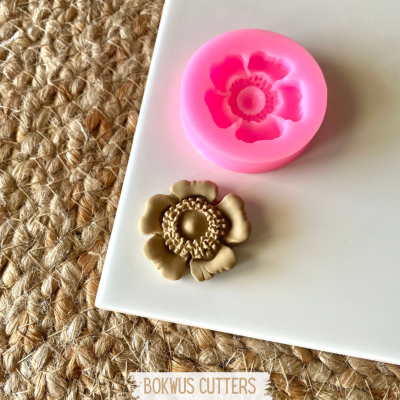 molde silicone rosa flor e peça moldada bege sobre placa branca e superfície de fibra natural