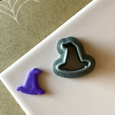 Forma metal para bolachas formato chapéu de bruxa e peça roxa cortada, com texto Halloween