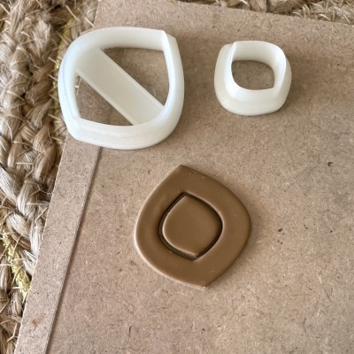 Três moldes plásticos coloridos sobre cartão castanho com tapete de fibra ao lado