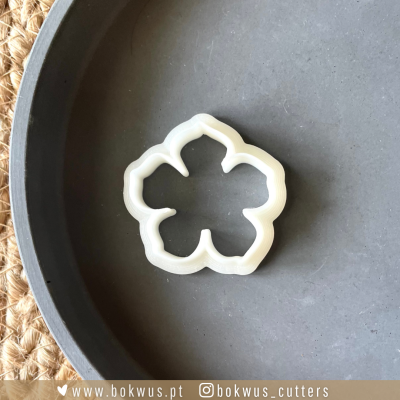 Cortador de bolachas branco em forma de flor sobre placa cinzenta
