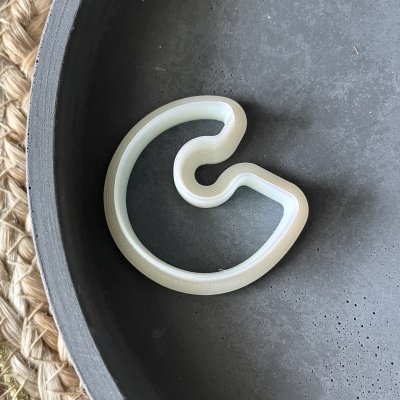 Gancho de plástico branco dentro de prato cinzento sobre tecido de palha.