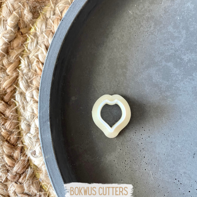 Cortador de biscoitos em forma de pimenta num prato cinza com tapete de fibras ao lado