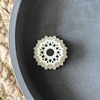 Anel decorativo branco com padrão recortado dentro de prato cinza fosco