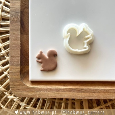 Cortador de biscoitos e biscoito em forma de esquilo em superfície branca e de madeira