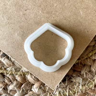 Cortador de biscoitos branco sobre cartão castanho e tecido rústico