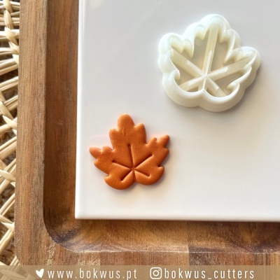 Cortador de massa branco em forma de folha com peça de massa laranja cortada