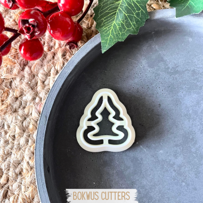 Cortador de biscoitos formato árvore de Natal em bandeja cinza com decoração verde e vermelha