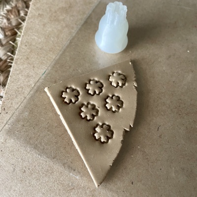 Massa bege com carimbos de flor e carimbo de silicone branco sobre superfície castanha