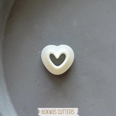 Forma de corte em plástico branco em forma de coração numa superfície cinzenta com texto BOKWUS CUTTERS