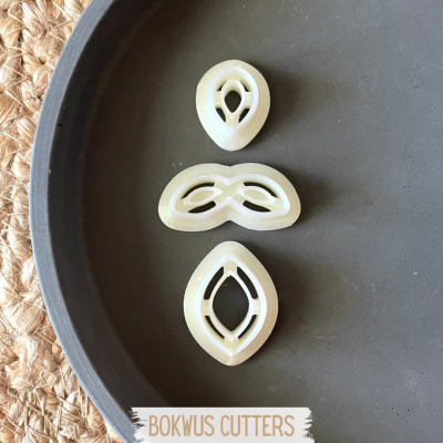 Três cortadores de massa creme em prato cinzento com texto BOKWUS CUTTERS