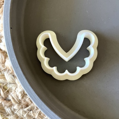 Cortador de biscoitos plástico branco formato asas numa superfície redonda cinzenta