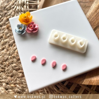 Moldes de silicone com flores decorativas coloridas em amarelo, azul e rosa sobre superfície branca