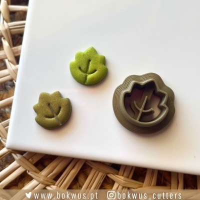 Conjunto de cortadores de biscoitos em forma de folhas sobre placa branca e superfície de rattan