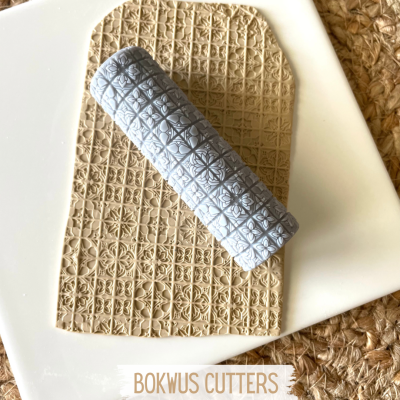 Rolo de massa cinzento com padrão em relevo e massa estampada sobre placa branca