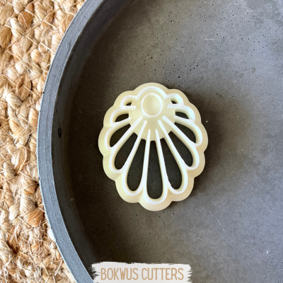 Cortador de bolachas em forma de concha branco em prato cinzento sobre fundo de juta