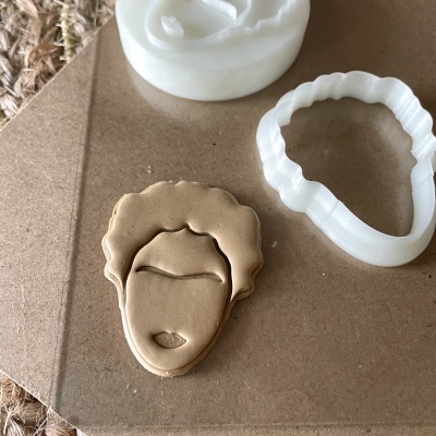 Conjunto de cortador branco de plástico para massa e massa moldada em forma de rosto feminino sobre cartão.