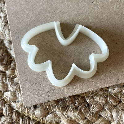 Cortador de bolachas branco em forma de folha sobre madeira e juta