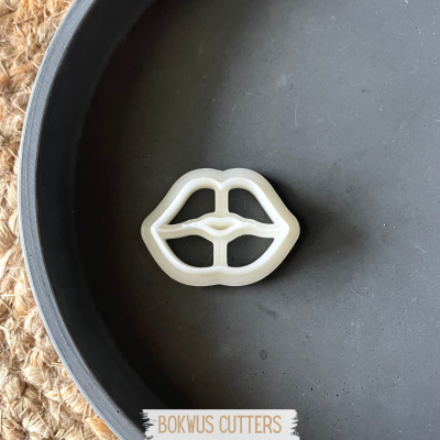 Cortador de bolachas em forma de lábios branco sobre prato preto