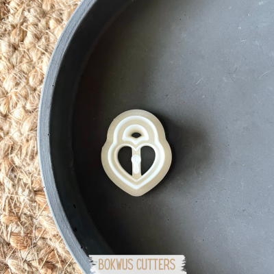 Cortador de biscoitos em forma de cadeado dentro de prato cinzento