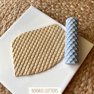 Rolo texturizador branco e placa de massa polimérica texturizada com padrão de escamas