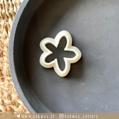 Cortador de massa em forma de flor de plástico branco sobre prato cinzento