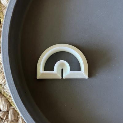 Peça branca semi-circular com fenda sobre superfície cinza escura