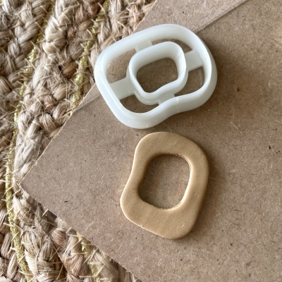 Cortador de plástico branco e forma cortada de massa bege sobre cartão e tapete de fibras naturais