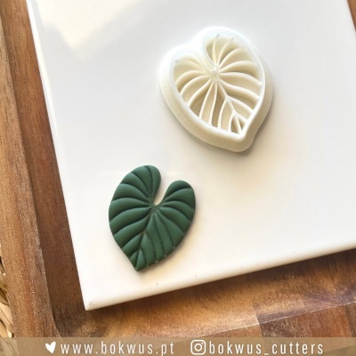 Dois cortadores de bolacha em forma de folha de peixe, um verde escuro e outro branco sobre prato branco