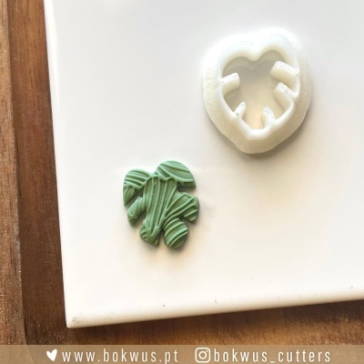 Molde branco de folha e peça verde detalhada numa superfície branca