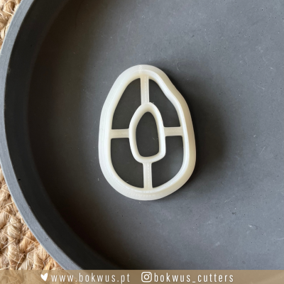 Cortador plástico branco formato abacate num prato cinza