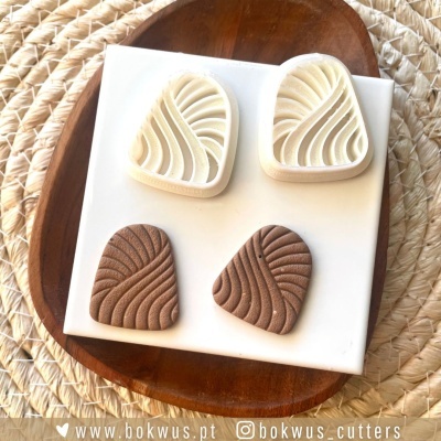 Cortadores triangulares com padrão abstracto em branco e castanho sobre base de madeira e tapete.