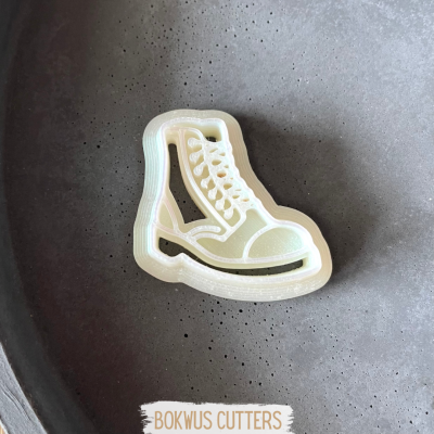 Cortador de biscoitos em forma de bota de cano alto creme sobre superfície preta