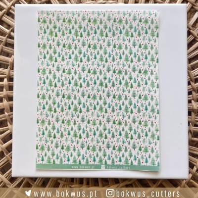 Pano de cozinha com padrão de árvores de Natal verdes e detalhes vermelhos sobre caixa branca