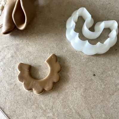 Cortador de massa branco em plástico com pedaço de massa cortado ao lado sobre superfície bege