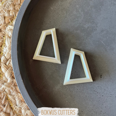 Dois cortadores trapezoidais creme em superfície escura com base de palha