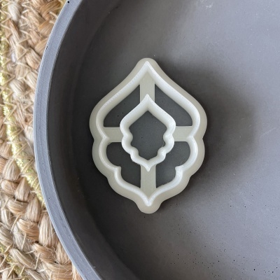 Forma de cortar biscoitos branca de plástico sobre prato cinzento redondo