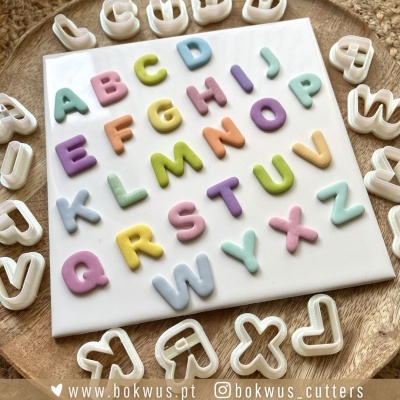 Cortadores de letras em plástico branco com letras de biscuit coloridas em tons pastel numa placa branca