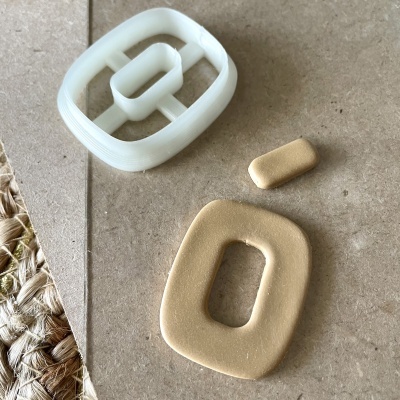 Molde branco e peças bege em fundo castanho claro com texto e superfície têxtil