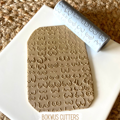 rolo de massa com padrões em relevo de seios sobre massa creme e base branca com tapete bege