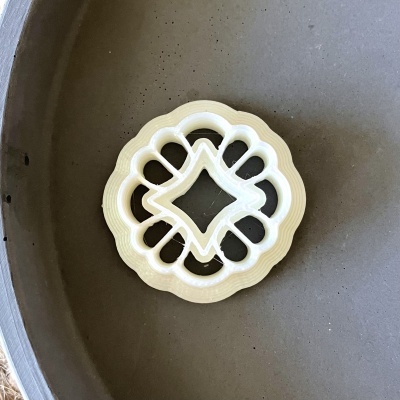 Cortador de biscoitos branco com padrão simétrico numa panela cinza