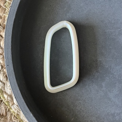 Anel plástico branco geométrico sobre superfície preta