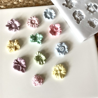 Flores decorativas coloridas e molde branco em silicona sobre superfície branca