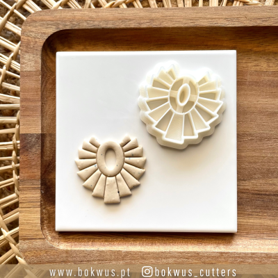 Cortador de biscoitos em formato de roseta e biscoito correspondente sobre fundo branco e bandeja de madeira