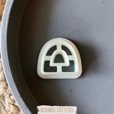 Cortador de biscoitos branco em forma de arco-íris numa superfície cinza redonda