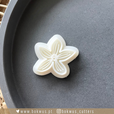 Cortador de massa em forma de flor branca sobre superfície preta