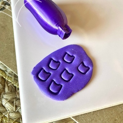 Carimbo roxo em forma de garrafa e massa de modelar roxa com marcas do carimbo sobre fundo branco com texto Halloween