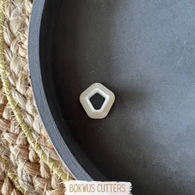 Cortador de massa branco com formato pentagonal dentro de prato preto